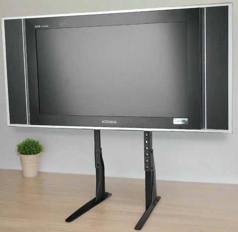 Universal black TV riser stand for 32 to 60 inch TVs
Side view of matte black adjustable TV desk mount
VESA-compatible desk mount for flat-screen TVs
TV stand setup for monitor or entertainment center use
Adjustable height tabletop TV stand with rubber feet