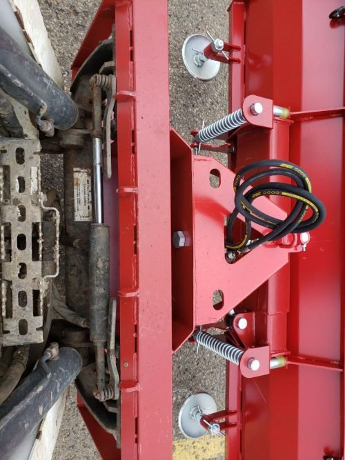 Skid steer clearing snow using Bendall hydraulic snow plow
Bendall 96” red snow plow angled to the side
Close-up of adjustable skid shoes and hydraulic fittings
Rear view of snow blade attached to skid steer
Bolt-on reversible cutting edge on Bendall plow