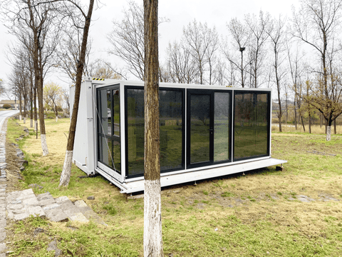 Expandable glass container house with black frame and white kitchen interior
20ft high cube glass container house on an outdoor plot
Modern prefab modular container home with large glass walls
Inside view of the container house kitchen and bathroom setup
portable luxury container home with plumbing and wiring