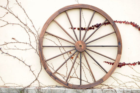 "Rustic wooden wagon wheel 48 inch for garden decor"
"Burnt wood wagon wheel leaning against a fence"
"Farmhouse yard display with decorative wooden wheels"
