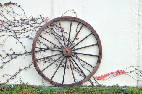 "Rustic wooden wagon wheel 48 inch for garden decor"
"Burnt wood wagon wheel leaning against a fence"
"Farmhouse yard display with decorative wooden wheels"