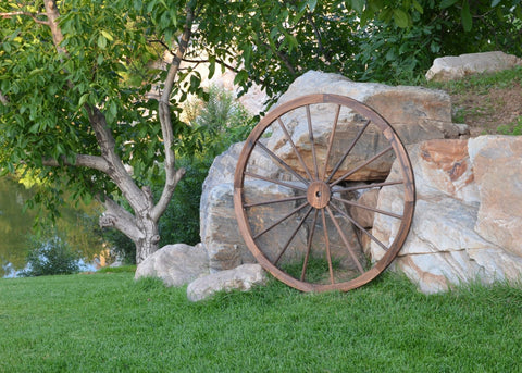 "Rustic wooden wagon wheel 48 inch for garden decor"
"Burnt wood wagon wheel leaning against a fence"
"Farmhouse yard display with decorative wooden wheels"