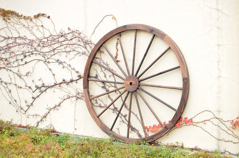 "Rustic wooden wagon wheel 48 inch for garden decor"
"Burnt wood wagon wheel leaning against a fence"
"Farmhouse yard display with decorative wooden wheels"