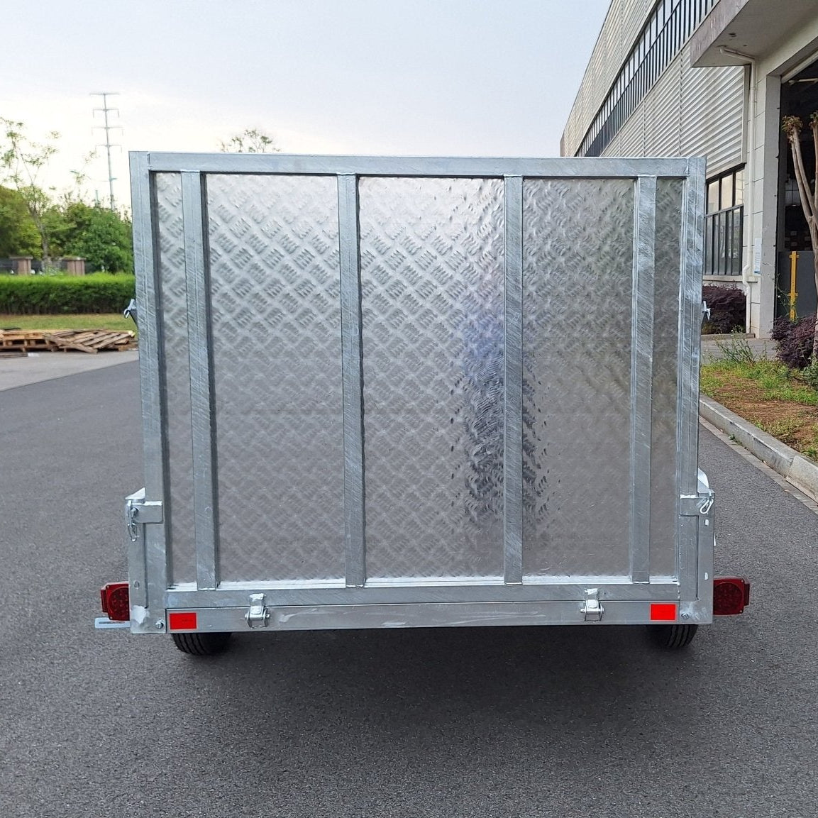 "5x8 galvanized utility trailer with built-in ATV ramps"
"Rust-resistant utility trailer parked near grass lot"
"Heavy-duty galvanized trailer with side view of ramps"