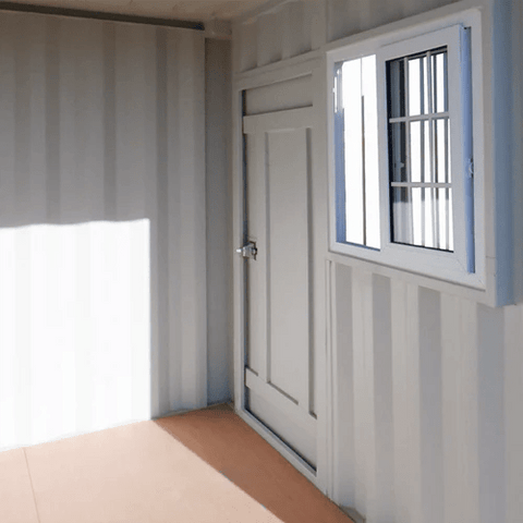 Gray 7FT steel office container with side door and windows
Interior view of 12FT jobsite office sea container
Office container unit with swing door and locking system
Plywood flooring inside portable office container
Security window with locking bar on steel sea container
