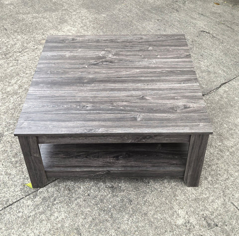 Dark gray oak square coffee table styled in a modern living room
Close-up of woodgrain texture and lower shelf
Angled view of the full table with storage items
The coffee table is placed with decorative accessories
Dark oak coffee table with books and a remote on the shelf