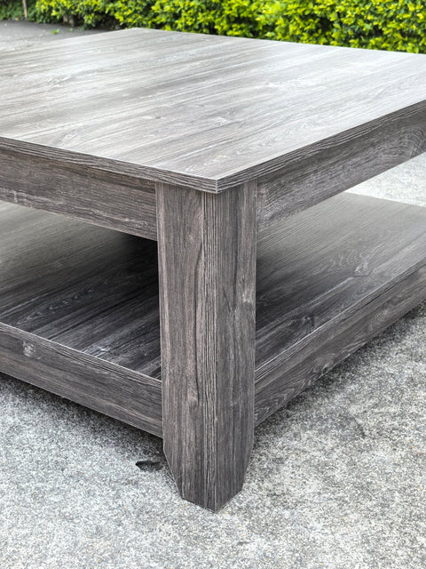 Dark gray oak square coffee table styled in a modern living room
Close-up of woodgrain texture and lower shelf
Angled view of the full table with storage items
The coffee table is placed with decorative accessories
Dark oak coffee table with books and a remote on the shelf