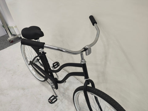 Side view of Deviant 26" beach cruiser bicycle in matte black
Close-up of comfort seat and handlebar grips
Rear coaster brake and single-speed drivetrain
Full assembled view of the Deviant black cruiser bike
Cruiser bike parked on a path at sunset