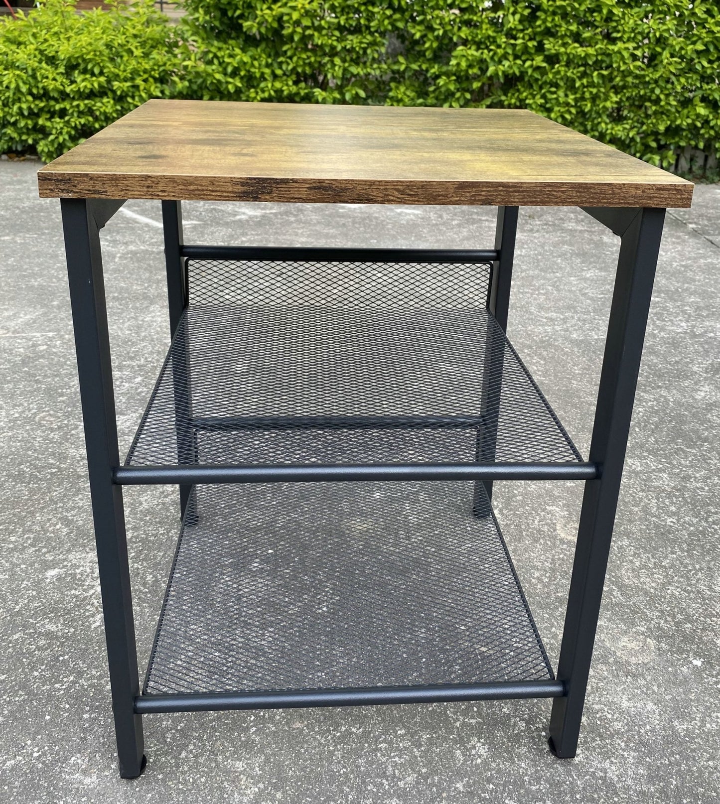 Rustic end tables in a cozy living room setting with sofa and lamp
Side View: Square wood top table with black mesh shelf
Angled View: Rustic wood and black metal table with adjustable shelf
Front View: Front profile of industrial end table with wood top and mesh shelf
Top View: Close-up of wood grain tabletop with rounded edges