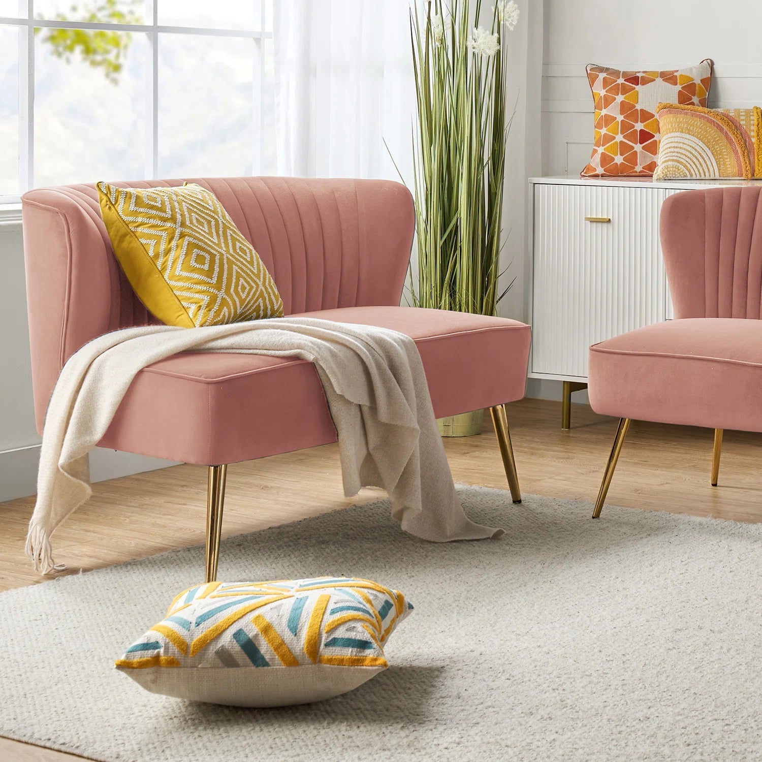 Fuchsia velvet loveseat with tufted back and gold legs in modern decor.
Ivory armless loveseat sofa with mid-century design in studio setup.
Tan velvet 2-seater with flared gold legs styled against a neutral wall.
Close-up of plush velvet texture and fluted backrest detail.
Color swatches displaying Fuchsia, Pink, Ivory, and Tan options.