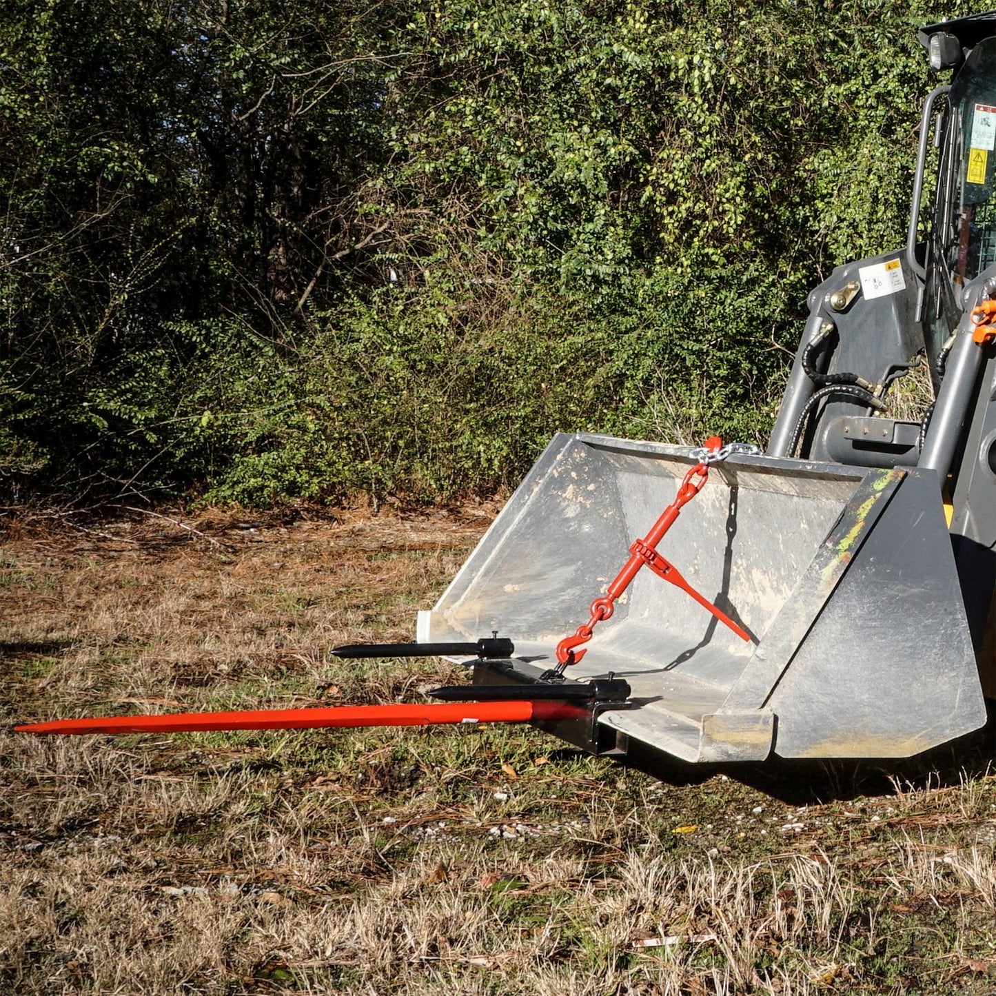 Triple Hay Bale Spears Attachment – Mounted on Loader

49-Inch Spear Fork Attachment – Top View

Bucket Attachment for Hay Bales – Side View

HY49 Red Steel Frame with Spears – Ground Placement

Close-up of Chains and Turnbuckle on Bucket Attachment

