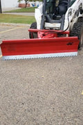 Skid steer clearing snow using Bendall hydraulic snow plow

Bendall 96” red snow plow angled to the side

Close-up of adjustable skid shoes and hydraulic fittings

Rear view of snow blade attached to skid steer

Bolt-on reversible cutting edge on Bendall plow