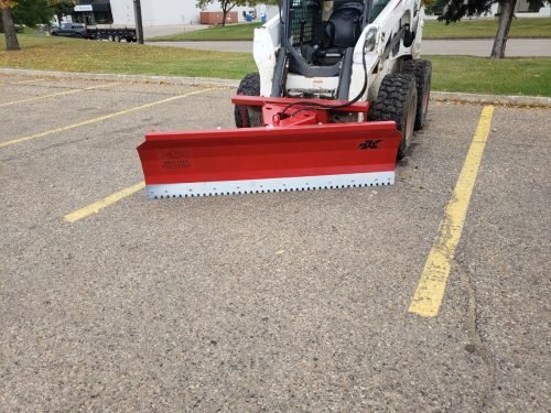 Skid steer clearing snow using Bendall hydraulic snow plow

Bendall 96” red snow plow angled to the side

Close-up of adjustable skid shoes and hydraulic fittings

Rear view of snow blade attached to skid steer

Bolt-on reversible cutting edge on Bendall plow