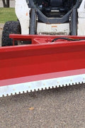 Skid steer clearing snow using Bendall hydraulic snow plow

Bendall 96” red snow plow angled to the side

Close-up of adjustable skid shoes and hydraulic fittings

Rear view of snow blade attached to skid steer

Bolt-on reversible cutting edge on Bendall plow