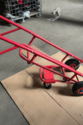 Red tire trolley cart with pneumatic wheels in garage

Heavy-duty tire dolly lifting tire set, ergonomic grip detail, welded frame close-up, tire stack in transit