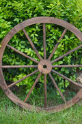 "Rustic wooden wagon wheel 48 inch for garden decor"

"Burnt wood wagon wheel leaning against a fence"

"Farmhouse yard display with decorative wooden wheels"
