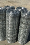 Rolled 330 FT livestock wire fence – silver steel

Close-up of barbed top and bottom wire fencing

Field wire fence rolls stacked on pallet – 4FT and 5FT

Product chart showing wire spacing and gauge specs