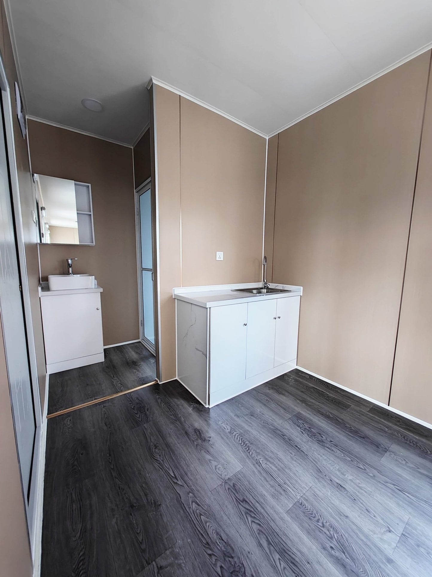 Exterior view of 40 FT insulated container office cabin

Interior layout showing vinyl flooring and workstations

TPS insulated walls and faux leather trim details

Plumbing and water system built into mobile cabin

Rear angle showing door and window design