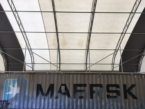 50x80 ft all-white PVC double truss fabric shelter installed over shipping containers – heavy-duty industrial storage building