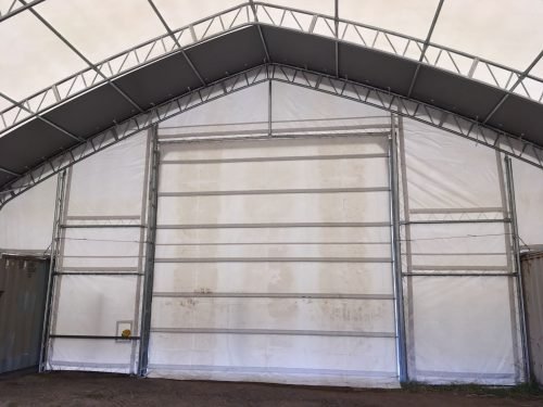 50x80 ft all-white PVC double truss fabric shelter installed over shipping containers – heavy-duty industrial storage building