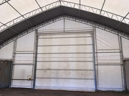 50x80 ft all-white PVC double truss fabric shelter installed over shipping containers – heavy-duty industrial storage building