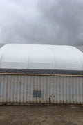 50x80 ft all-white PVC double truss fabric shelter installed over shipping containers – heavy-duty industrial storage building