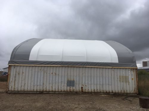 50x80 ft all-white PVC double truss fabric shelter installed over shipping containers – heavy-duty industrial storage building