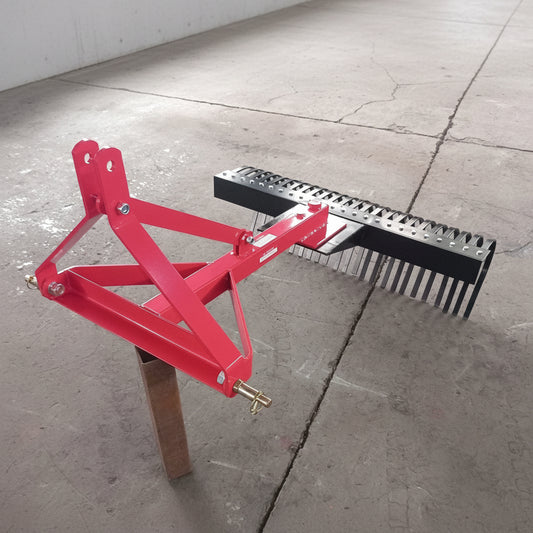 Red 5 FT landscape rake for tractor with 3-point hitch

Side view of landscape rake attachment on concrete

Close-up of tine design and mounting frame

3-point hitch mount landscape rake back view