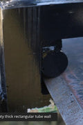 Heavy-duty clamp-on pallet forks attached to tractor bucket
Side view of 60-inch pallet forks with stabilizer bar
Close-up of fork clamps and locking bolts
Rear view showing rollback guard on pallet fork
Forks lifting lumber/crates on farm terrain