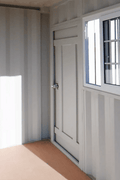 Gray 7FT steel office container with side door and windows
Interior view of 12FT jobsite office sea container
Office container unit with swing door and locking system
Plywood flooring inside portable office container
Security window with locking bar on steel sea container