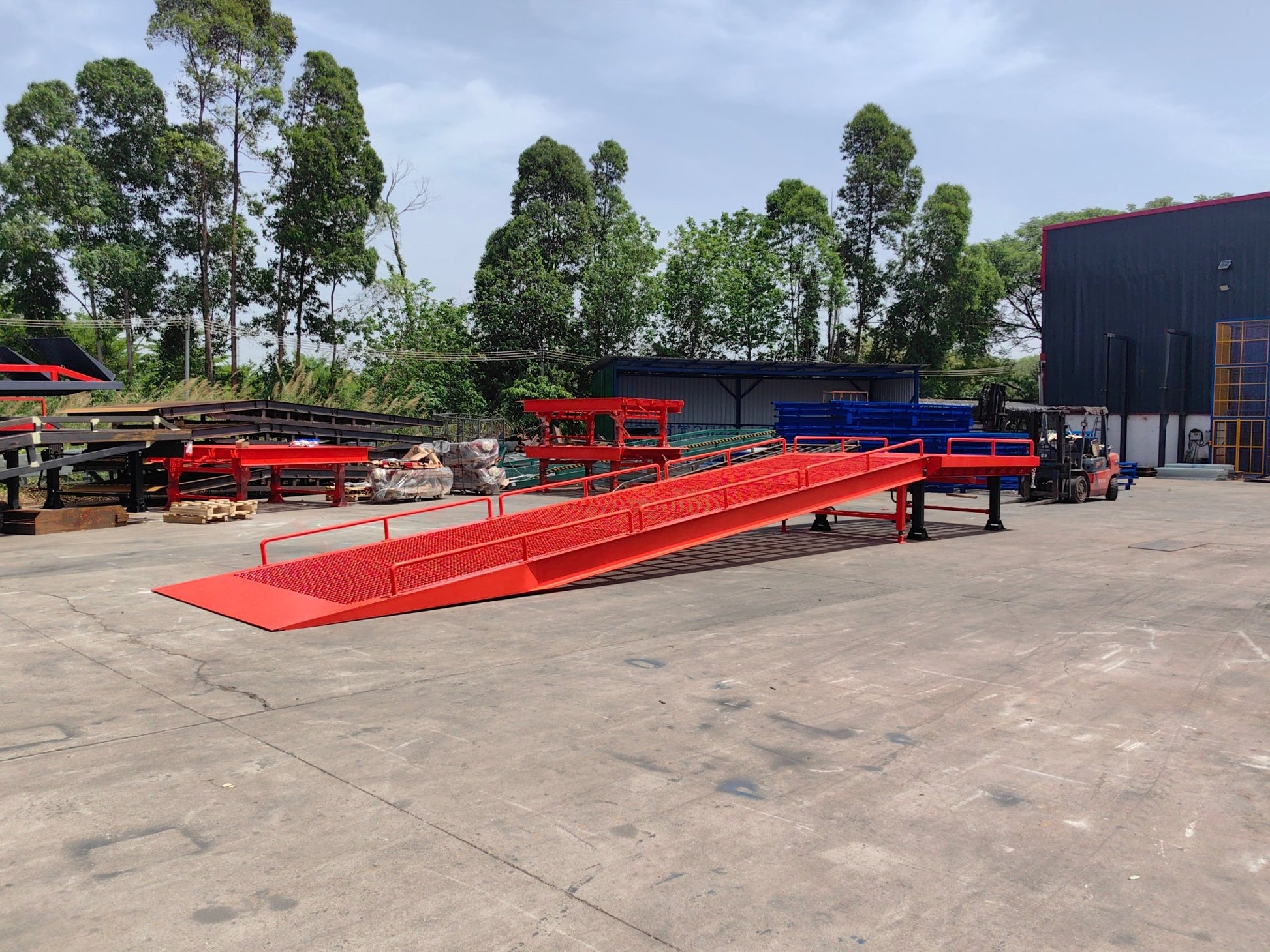 Heavy-duty loading dock ramp with red grating on asphalt yard

Forklift-compatible yard ramp side view with guardrails

Industrial dock ramp base plate and wheels

Side profile of 8 ft wide portable dock ramp

Ramp surface with serrated anti-slip steel close-up