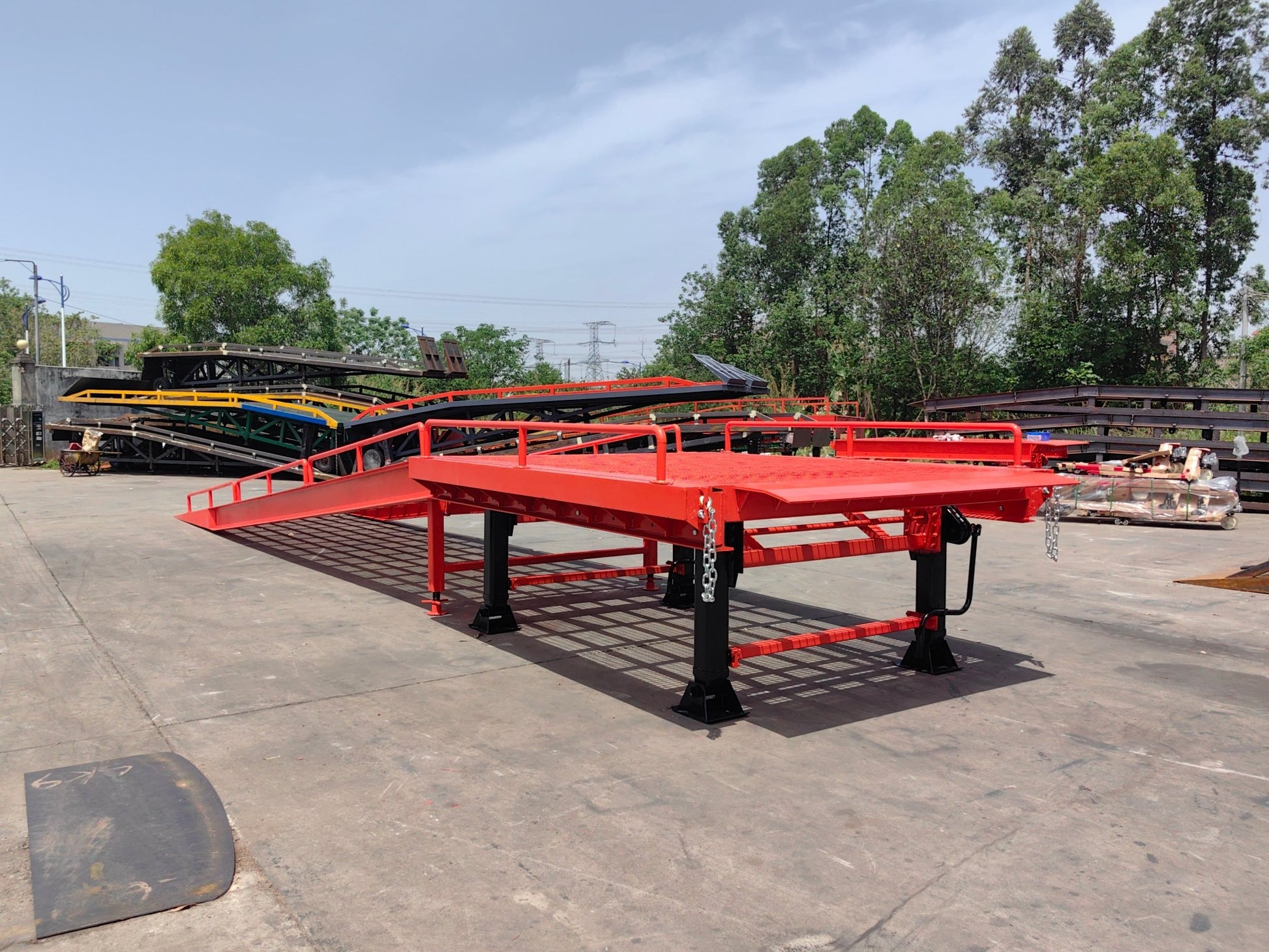 Heavy-duty loading dock ramp with red grating on asphalt yard

Forklift-compatible yard ramp side view with guardrails

Industrial dock ramp base plate and wheels

Side profile of 8 ft wide portable dock ramp

Ramp surface with serrated anti-slip steel close-up