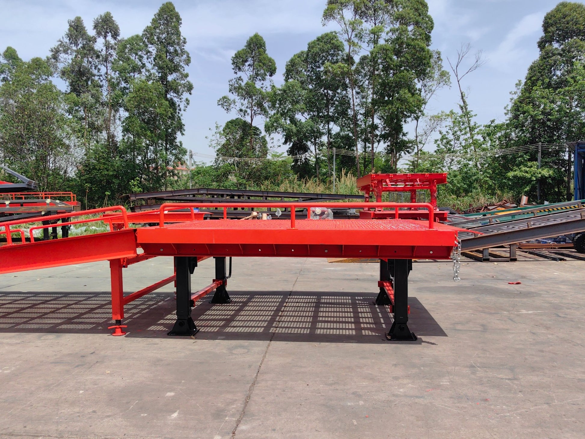 Heavy-duty loading dock ramp with red grating on asphalt yard

Forklift-compatible yard ramp side view with guardrails

Industrial dock ramp base plate and wheels

Side profile of 8 ft wide portable dock ramp

Ramp surface with serrated anti-slip steel close-up