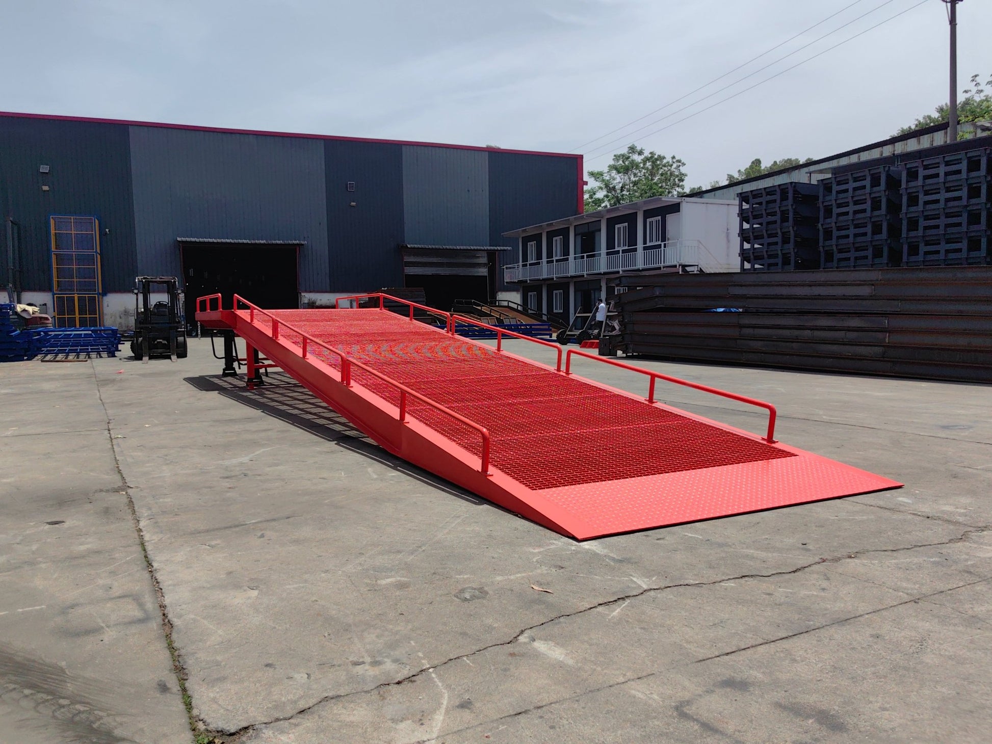 Heavy-duty loading dock ramp with red grating on asphalt yard

Forklift-compatible yard ramp side view with guardrails

Industrial dock ramp base plate and wheels

Side profile of 8 ft wide portable dock ramp

Ramp surface with serrated anti-slip steel close-up