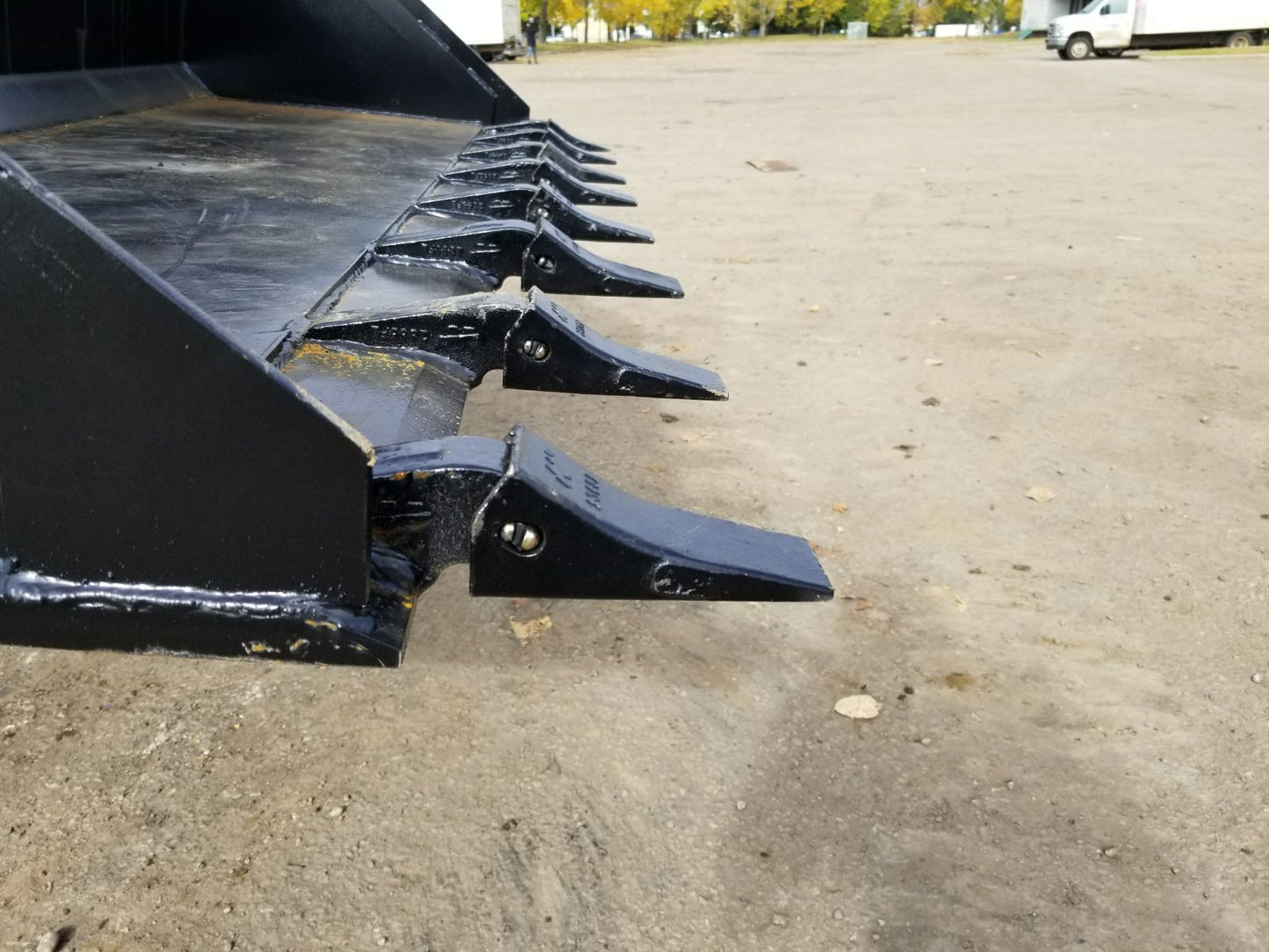 80" skid steer digging bucket with removable teeth

Heavy-duty bucket on job site with loader

Front view of 84-inch skid steer bucket

Skid steer digging into dirt with steel bucket

Wear strips and teeth close-up for material handling