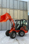 CanLift Mini Wheel Loader with Kubota D1703 engine, orange color – front view
Side view of CanLift compact loader with closed cabin and bucket raised
CanLift mini loader in operation – orange machine on construction site