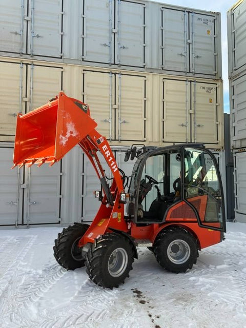 CanLift Mini Wheel Loader with Kubota D1703 engine, orange color – front view
Side view of CanLift compact loader with closed cabin and bucket raised
CanLift mini loader in operation – orange machine on construction site