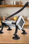 Deluxe stainless steel French fry cutter with suction feet on wood countertop