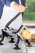 Manual potato slicer in action cutting fresh fries with ergonomic handle
