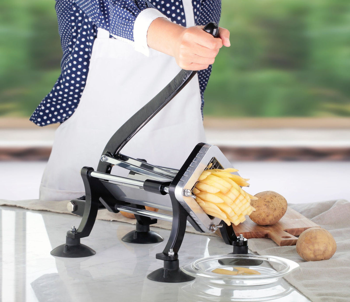Manual potato slicer in action cutting fresh fries with ergonomic handle