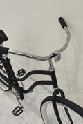 Side view of Deviant 26" beach cruiser bicycle in matte black

Close-up of comfort seat and handlebar grips

Rear coaster brake and single-speed drivetrain

Full assembled view of the Deviant black cruiser bike

Cruiser bike parked on a path at sunset