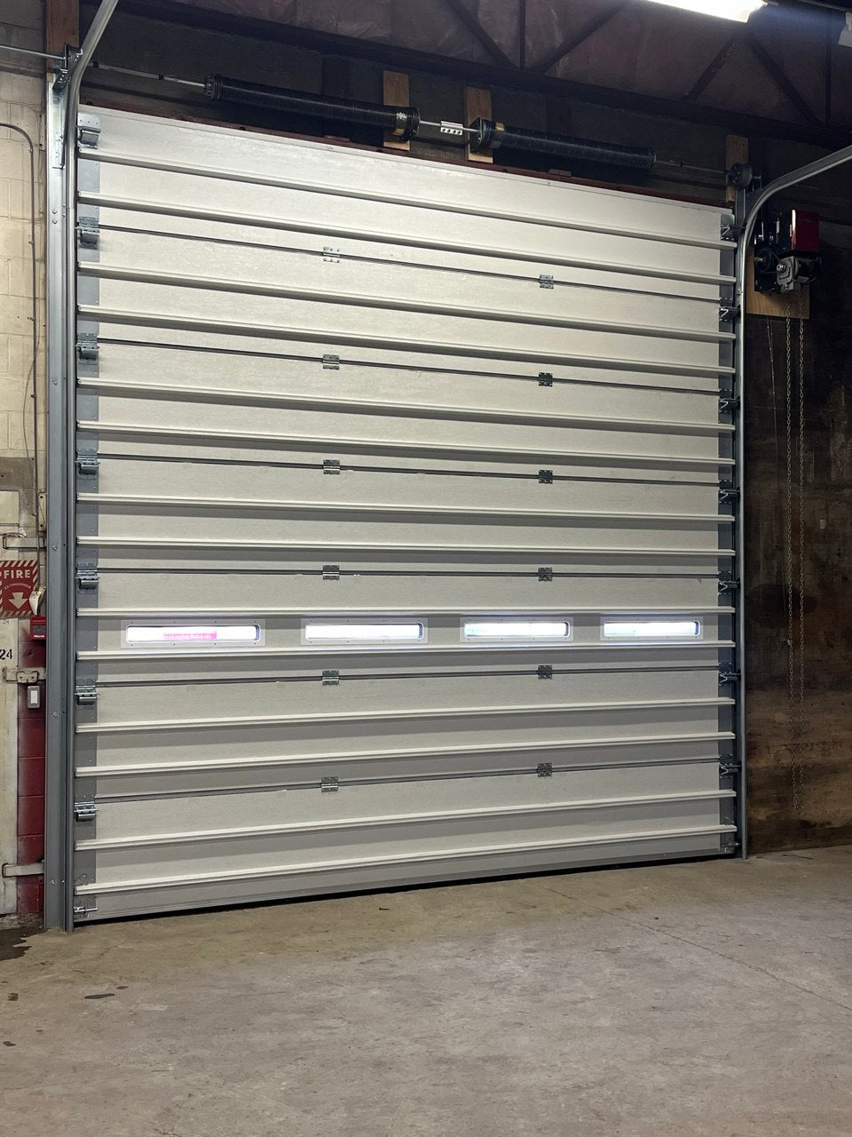 White insulated electric overhead garage door installed in shop
Heavy-duty motorized overhead garage door with steel frame
Electric garage door kit with insulation for industrial buildings
Overhead sectional garage door installed on warehouse