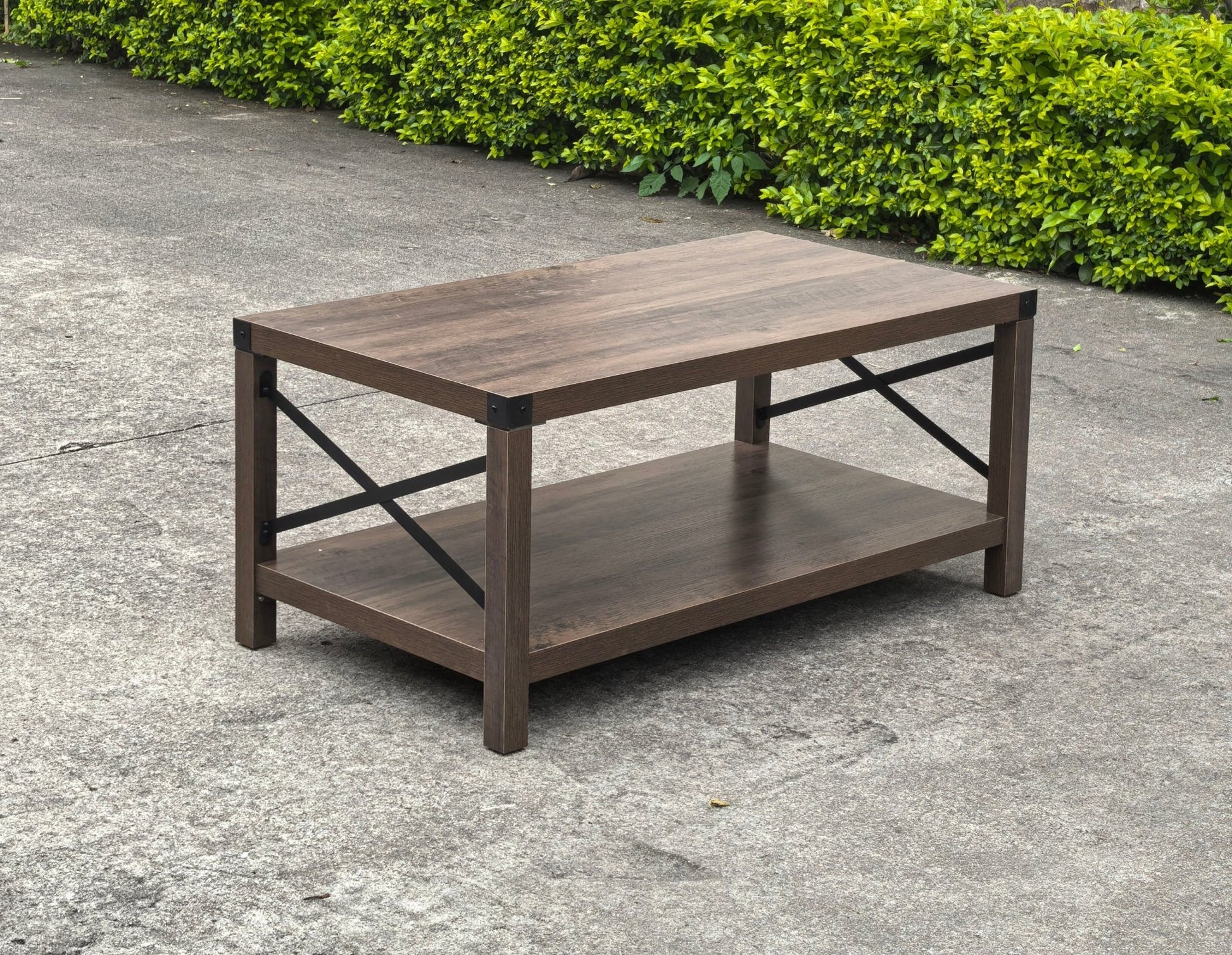 Gray wash rustic coffee table with metal X-frame in the living room
Front view of the coffee table showing shelf storage
Side angle showing gray tabletop and open shelf
Coffee table outdoors with accessories
Detail of gray wash wood and black frame