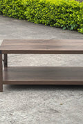 Gray wash rustic coffee table with metal X-frame in the living room
Front view of the coffee table showing shelf storage
Side angle showing gray tabletop and open shelf
Coffee table outdoors with accessories
Detail of gray wash wood and black frame