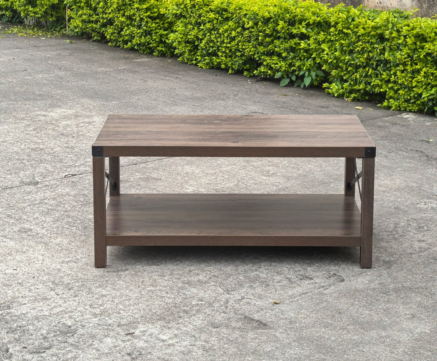 Gray wash rustic coffee table with metal X-frame in the living room
Front view of the coffee table showing shelf storage
Side angle showing gray tabletop and open shelf
Coffee table outdoors with accessories
Detail of gray wash wood and black frame