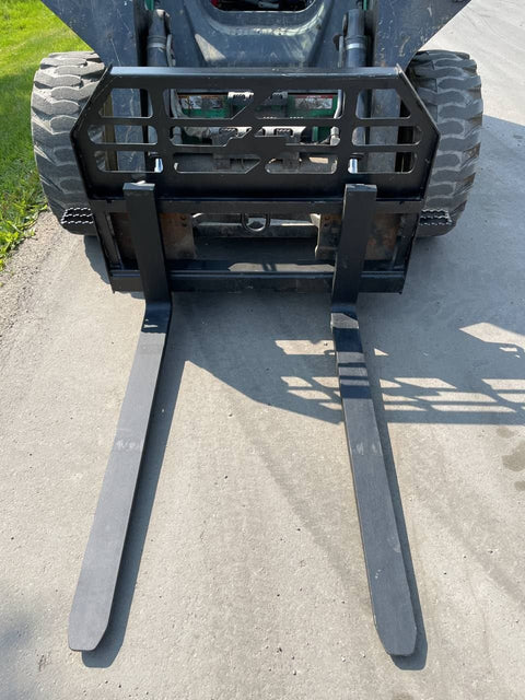 Heavy-duty skid steer pallet forks lifting a load

CNC carriage bar with quick attach mounting

Close-up of forks locked in carriage slots

Side step feature on fork frame

Variants of 48", 60", 72", and 96" forks shown on pallet