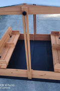 Wooden sandbox with canopy fully extended and benches visible

Close-up of sandbox lid cover in closed position

Children playing inside wooden sandbox with canopy

Side angle showing bench detail and canopy fabric

Folded sandbox closed with protective cover on top