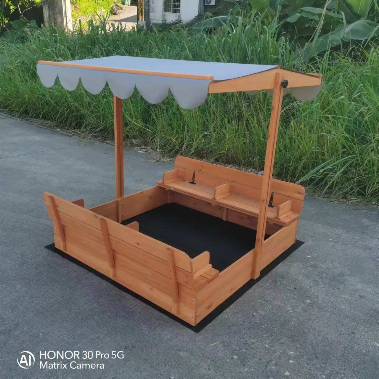 Wooden sandbox with canopy fully extended and benches visible

Close-up of sandbox lid cover in closed position

Children playing inside wooden sandbox with canopy

Side angle showing bench detail and canopy fabric

Folded sandbox closed with protective cover on top