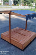 Wooden sandbox with canopy fully extended and benches visible

Close-up of sandbox lid cover in closed position

Children playing inside wooden sandbox with canopy

Side angle showing bench detail and canopy fabric

Folded sandbox closed with protective cover on top