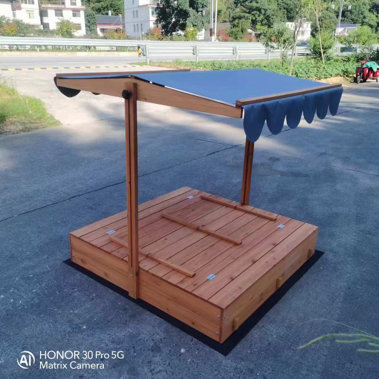 Wooden sandbox with canopy fully extended and benches visible

Close-up of sandbox lid cover in closed position

Children playing inside wooden sandbox with canopy

Side angle showing bench detail and canopy fabric

Folded sandbox closed with protective cover on top